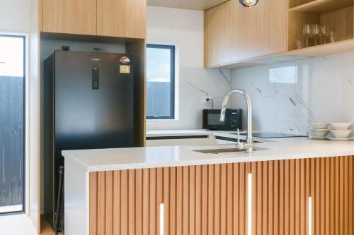 una cucina con frigorifero nero e lavandino di Cozy 2 Bedroom Waterview Home for Work and Family ad Auckland