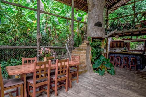 a dining room with a table and chairs and a tree at Casa Aviari in Cabo Matapalo