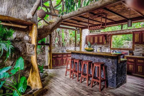 an outdoor kitchen with a bar and stools at Casa Aviari in Cabo Matapalo