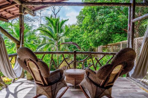 a porch with two chairs and a table and trees at Casa Aviari in Cabo Matapalo