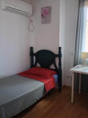 a small bedroom with a bed with a red pillow at Tu Hogar en Ronda in Ronda