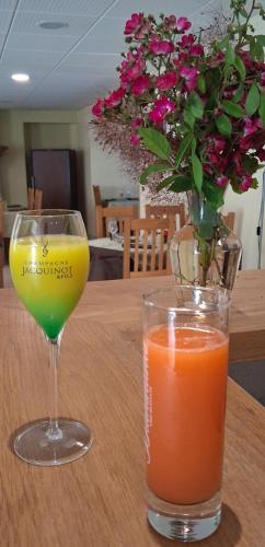 a glass of juice and a vase with flowers on a table at Logis hôtel l'instant Mont le Viaur in Saint-André-de-Najac