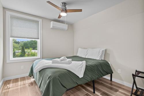 Un dormitorio con una cama con ventilador y una ventana. en Sweet Solitude On Main, en Warrensburg