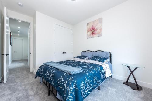 a bedroom with a bed with a blue comforter at Luxury Home Near DT, New Build, High-End Features in Calgary