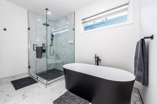 a bathroom with a bath tub and a glass shower at Luxury Home Near DT, New Build, High-End Features in Calgary