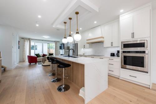 a kitchen with white cabinets and a kitchen island with bar stools at Luxury Home Near DT, New Build, High-End Features in Calgary