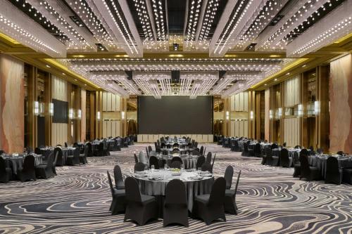 a ballroom with tables and chairs and a projection screen at JW Marriott Hotel and Suites Saigon in Ho Chi Minh City