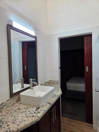a bathroom with a sink and a mirror and a bed at My Beach House in Tela