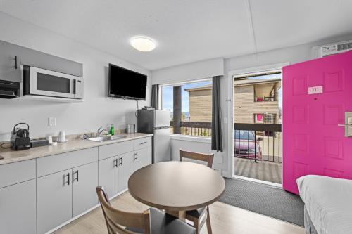 a kitchen with a pink door and a table at The Vista Inn in Kamloops