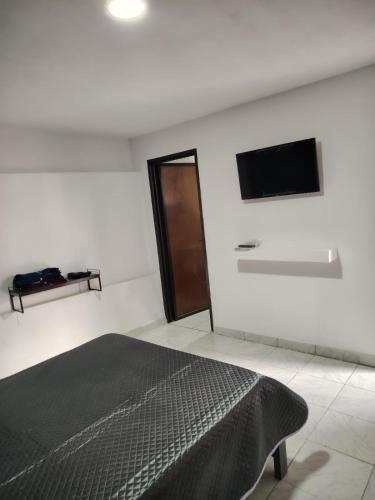 a bedroom with a bed and a flat screen tv at minidepartamento a unos pasos de la gran pirámide in Cholula