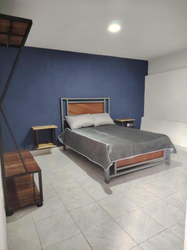 a bedroom with a bed and a blue wall at minidepartamento a unos pasos de la gran pirámide in Cholula