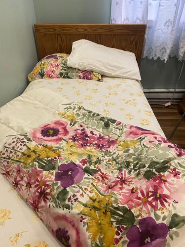 a bed with a floral comforter on it at Peaceful and Private Small Room in Brampton
