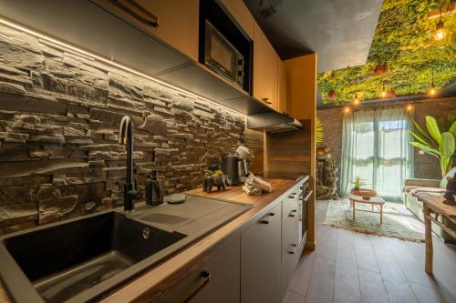 a kitchen with a sink and a stone wall at La Jungle Evasion, séjour immersif en famille in Hennebont