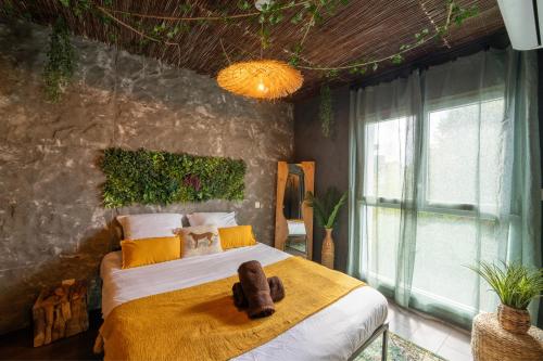 a bedroom with a large bed with a yellow blanket at La Jungle Evasion, séjour immersif en famille in Hennebont