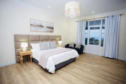 a bedroom with a large bed and a chair at Illi Boutique Guest House in Durban