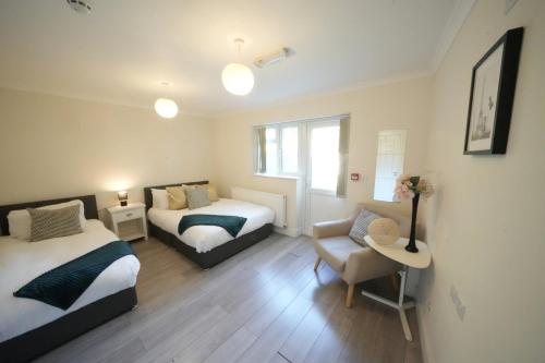 a bedroom with two beds and a couch and a chair at The Close Airport in Harmondsworth