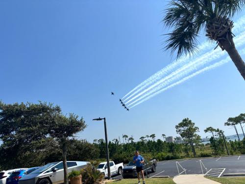 a man standing in a parking lot watching an airplane at Ocean Serenity in Pensacola