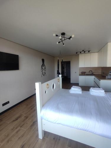 a large white bed in a room with a kitchen at Тематичні апартаменти in Zhytomyr