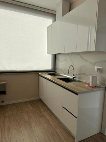 a kitchen with white cabinets and a sink and a window at Air B&B Hotel in Rrëshen