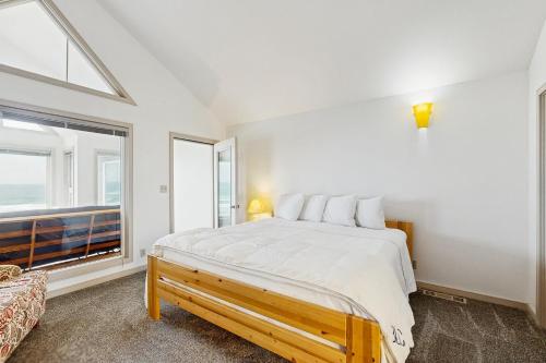 a white bedroom with a large bed and a window at Beach Loop Condo #2 - South Unit in Bandon