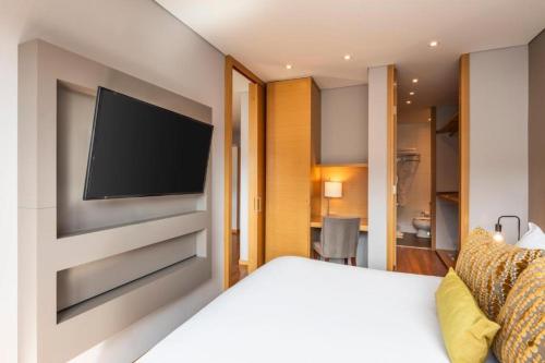 ボゴタにあるHotel 93 Luxury Suites by Preferredのベッドルーム1室(ベッド1台、壁掛け式薄型テレビ付)
