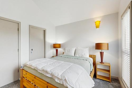 a bedroom with a bed with white sheets and two lamps at Beach Loop Condo #2 - South Unit in Bandon