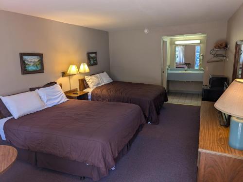 a hotel room with two beds and a bathroom at Coach Stop Motel in Wellsboro