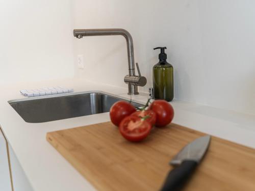 a kitchen counter with a sink and tomatoes on a cutting board at Modernes Hostel, Privatzimmer in Shared Apartment- 6min zur Olma Messe in St. Gallen
