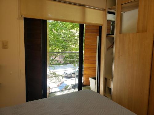 a bedroom with a bed and a large window at Casa patio y parrillero in Montevideo