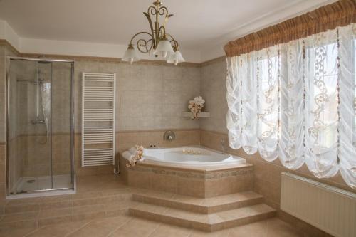 a bathroom with a tub and a shower with curtains at Villa Grande - Apartmány in Olomouc