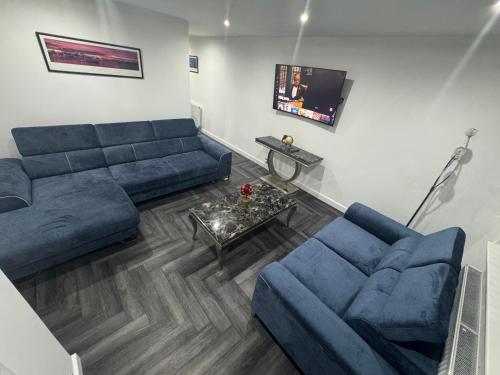 a living room with two blue couches and a tv at Modern 3 Bedroom Holiday Home -Jaquzzi Bath -Private Parking-suitable for contractors - Free WiFi in Beeston