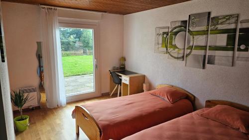 Un dormitorio con dos camas y un escritorio y una ventana. en Appartement le Refuge du Cerisier, en La Chaux-de-Fonds