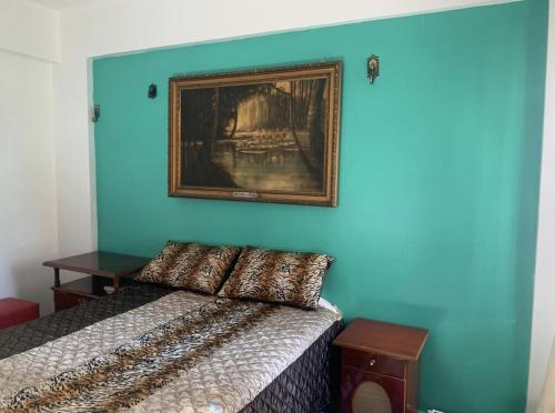 a blue wall with a picture above a bed at Casa de Francisco in Belém