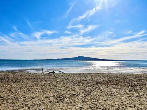 a sandy beach with a view of the ocean at Charming Guest House in the Bays in Auckland