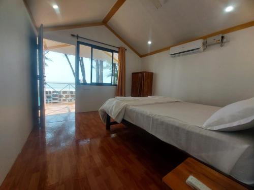 une chambre avec deux lits et une grande fenêtre dans l'établissement Nikhils Luxury Beach Cottages, à Magdāl