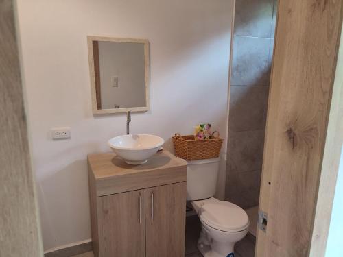 a bathroom with a sink and a toilet and a mirror at Casa de Campo Riverside in Puerto Quito