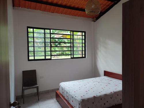 a bedroom with a bed and a window at Casa de Campo Riverside in Puerto Quito