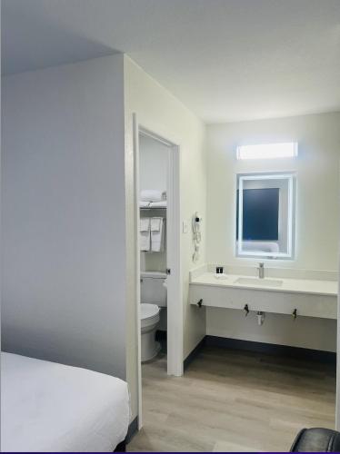 a white bathroom with a sink and a toilet at Hallmark Inn & Suites Newly Renovated Rooms San Antonio Northeast in San Antonio
