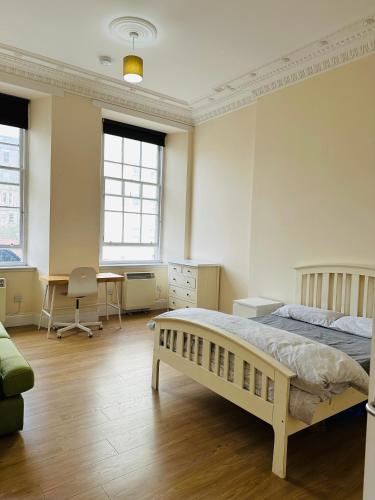 グラスゴーにあるMaster Bedroom in City Centerのベッドと机と2つの窓がある寝室
