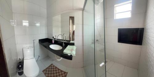a white bathroom with a sink and a shower at Casa Jardins in Barreirinhas