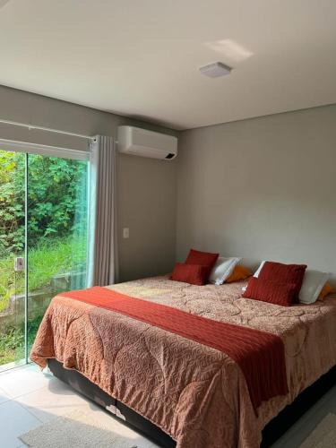 Un dormitorio con una cama con almohadas rojas y una ventana. en Apartamento Morada Madu, No Centrinho da Praia do Rosa, en Imbituba