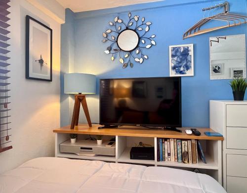 a bedroom with a tv and a blue wall at Petit Bonheur - Calm Intimate - Terrace & Beach in Puerto Vallarta