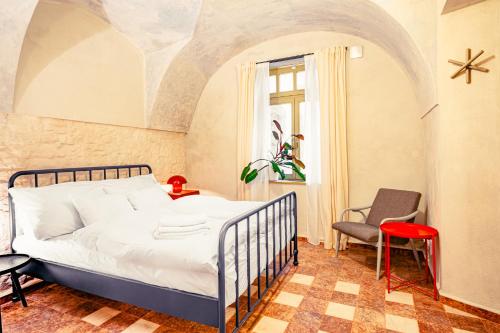 a bedroom with a bed and a chair at Apartmány Oblouk - stylové ubytování v historickém jádru města in Žatec