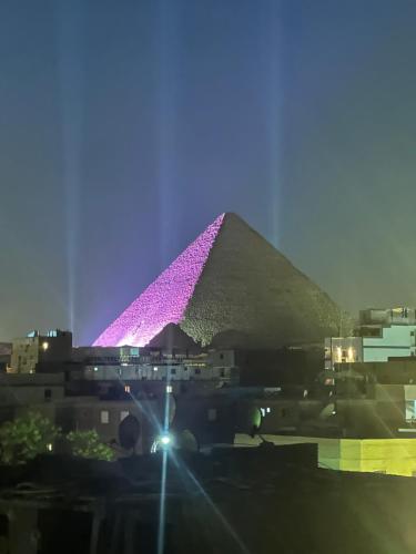 a pyramid is lit up purple at night at Great Pyramid Lodge in Cairo