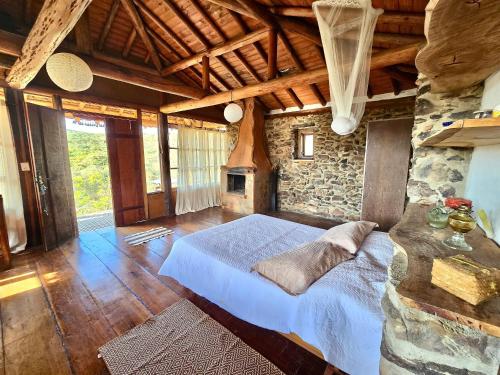 a bedroom with a bed and a stone wall at Chalés Vila Carrancas - Unidade Serra in Carrancas