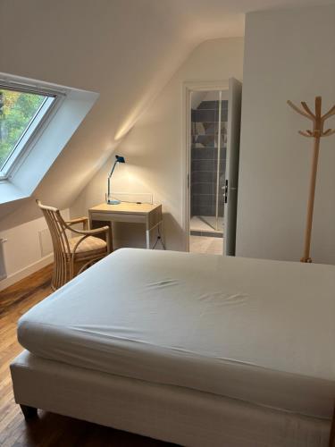 ロリアンにあるLe premier etage indépendant dans une maison avec grand parcのベッドと机と窓のある寝室