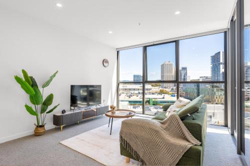a living room with a green couch and a large window at Central Woden Stay, Near Hospital, CIT, Pool in Phillip