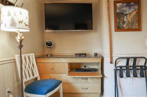 a room with a desk with a television and a chair at Yellowstone Gateway Inn in Gardiner