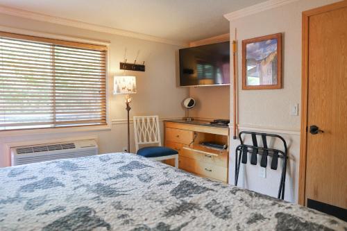 a bedroom with a bed and a desk and a window at Yellowstone Gateway Inn in Gardiner