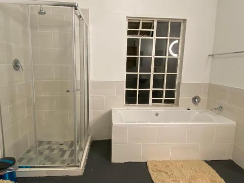 a bathroom with a shower and a white tub at Fiet Star in Midrand